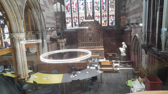 View from above looking down on tables that are in front of the stained glass and altar of a converted church