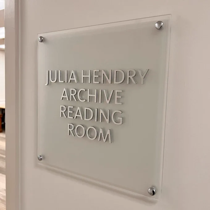 Glass sign with silver letters on the wall outside the Laurier Archives and Special Collections. Reads Julia Hendry Archive Reading Room.