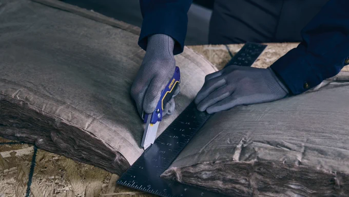Image of someone using a ProFlip™ 3-Blade Folding Utility Knife to cut through insulation. 