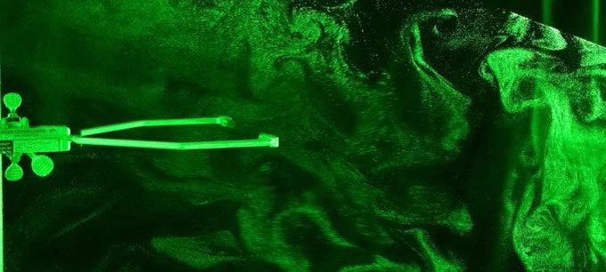 Photo of swirling air and cloud droplets in a cloud chamber, lit by green light