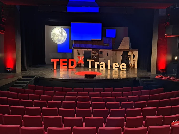 A photo of the Ted X Tralee Stage with a set of an old Irish country kitchen theme behind the Ted X Tralee signage.