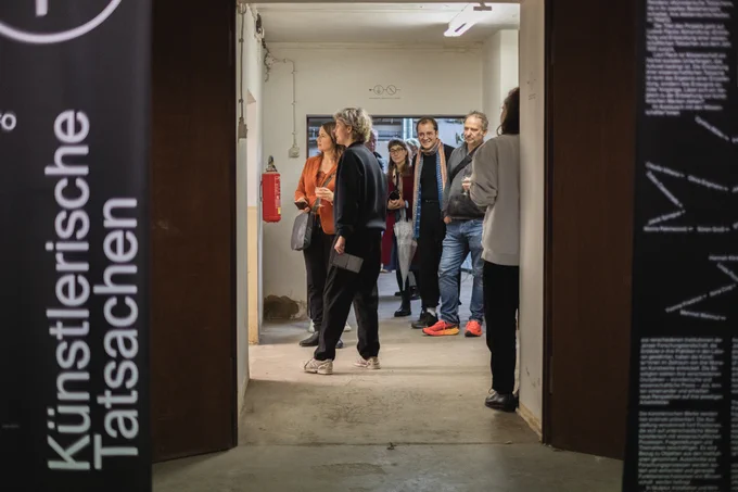 Blick in den Flur mit kT-Ausstellungsbannern und einer Menschengruppe im Hintergrund. 