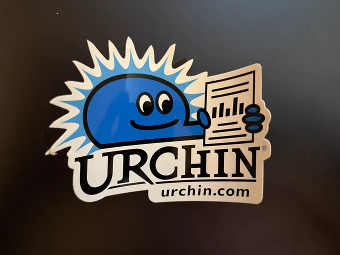 a die cut vinyl sticker for urchin.com showing a friendly blue smiling urchin holding a report with a histogram in the middle. the sticker is from 1999.