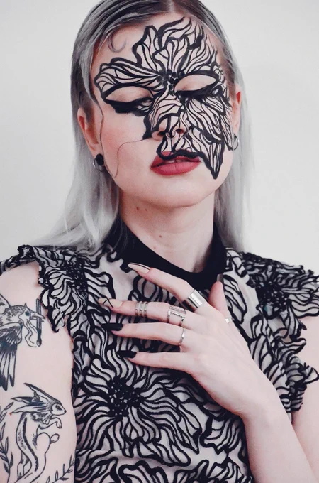 me with a big excessive black linework flower drawn on my face, looking all dramatic about it