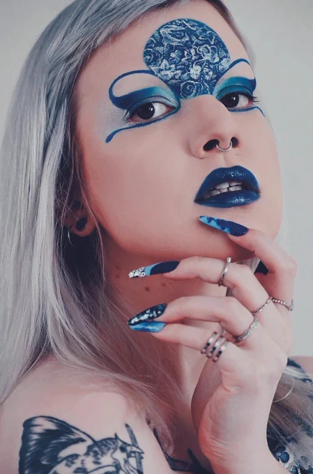 my face again but with blue graphic eyeliner and a big blue circle in the middle of my forehead with a silver floral pattern painted on it