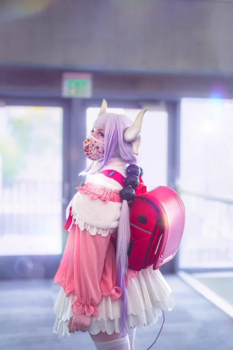 Photo shot from a back 3/4 angle of a pink and white dress with a big red backpack.  Hair is light purple to dark purple gradient, with white horns and black hair bobbles.