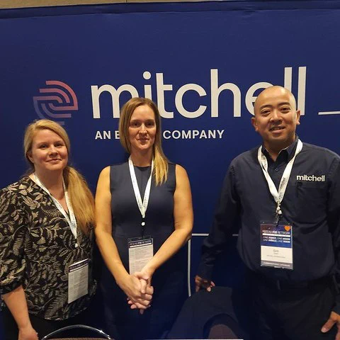 Three Mitchell team members standing in front of Mitchell booth. 