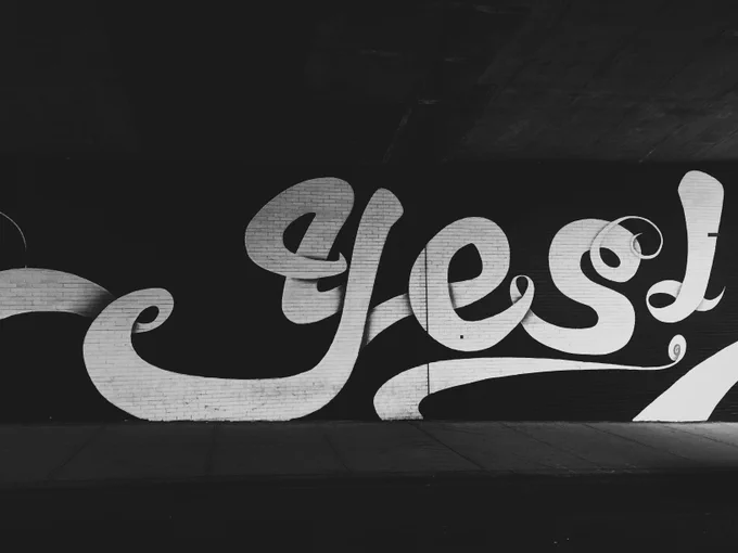 B/w graffiti on brick wall. Photo by @jontyson on Unsplash.
  