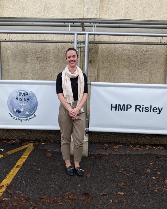 Woman stood in front of HMP Risley sign