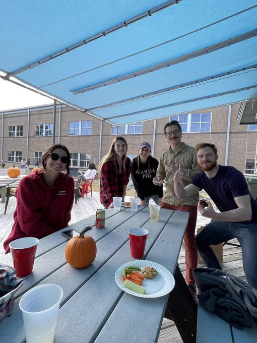 Five students gather at a picnic table
