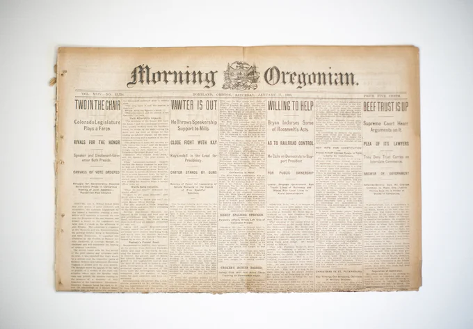 The front page of the 1905 Morning Oregonian is shown, with four headlines about local politics and business across the top and columns of very small text