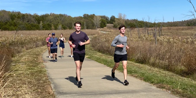 A group of students run during the Women in Law 5K fun run on the trails at Clinton Lake
