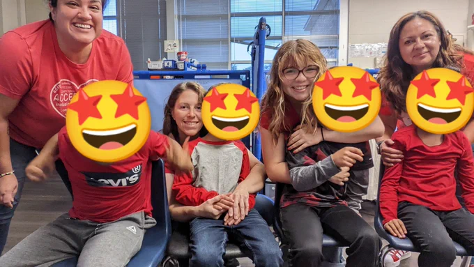 4 students wearing red shirts, with star eye emojis over their faces, sitting in a row with 4 teachers behind them.