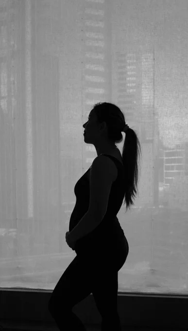 second trimester side profile in black and white standing in front of high rises in Hong Kong