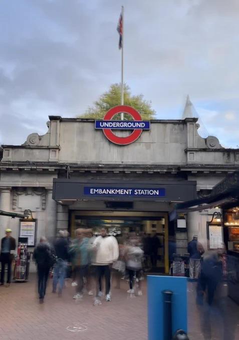 A London Underground station with people entering and exiting.