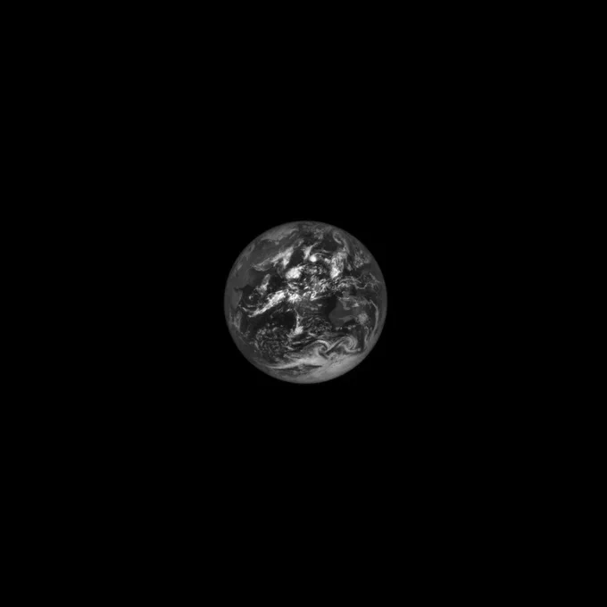 The full Earth appears as sphere against the blackness of space in this black-and-white view. Continents, oceans, and swirling clouds are visible.