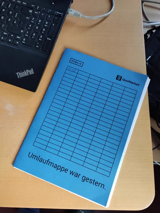 Eine blaue Umlaufmappe auf einem Schreibtisch. Auf der Mappe steht "Umlaufmappe war gestern"