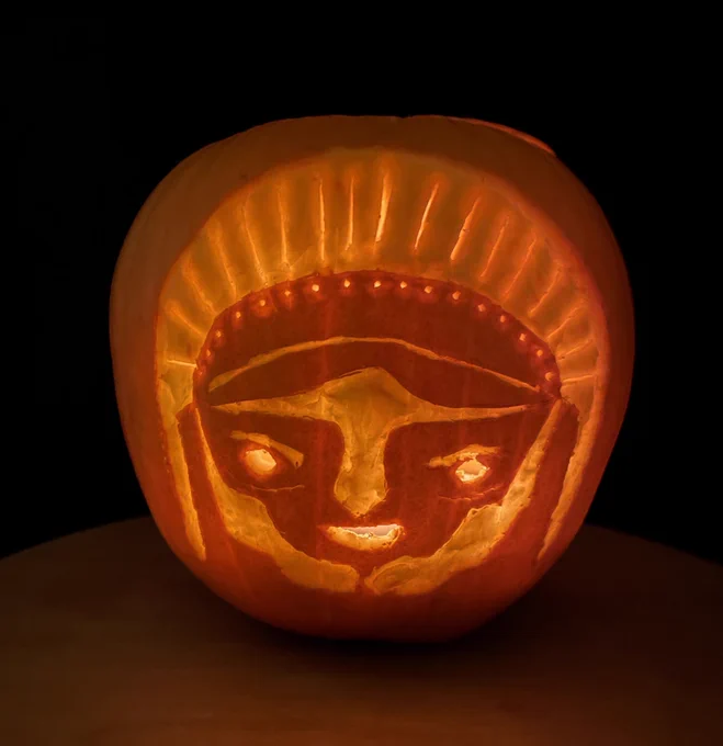 A pumpkin carved with a design of facing Athena in a created helmet