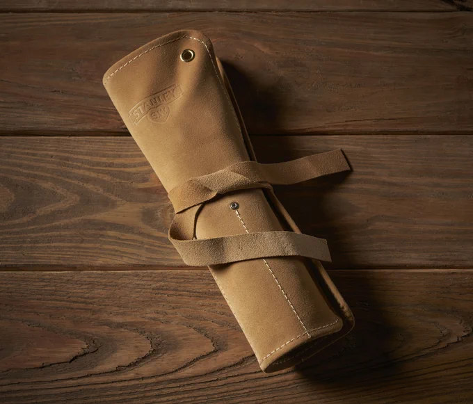 A leather tool roll resting on a wooden table. 