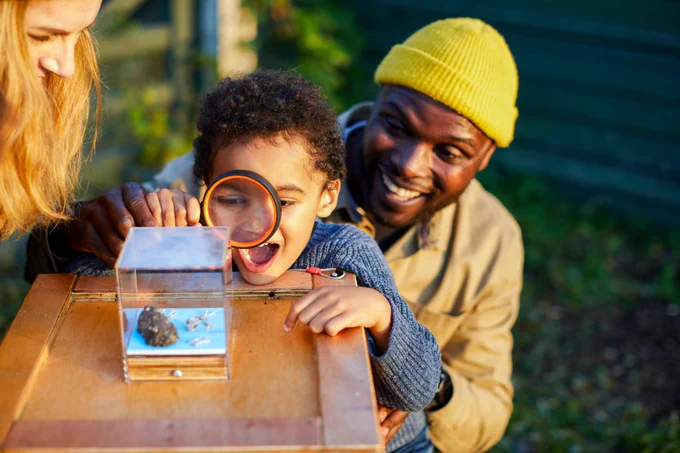 Child looking at plants and living things closely through a magnifying glass