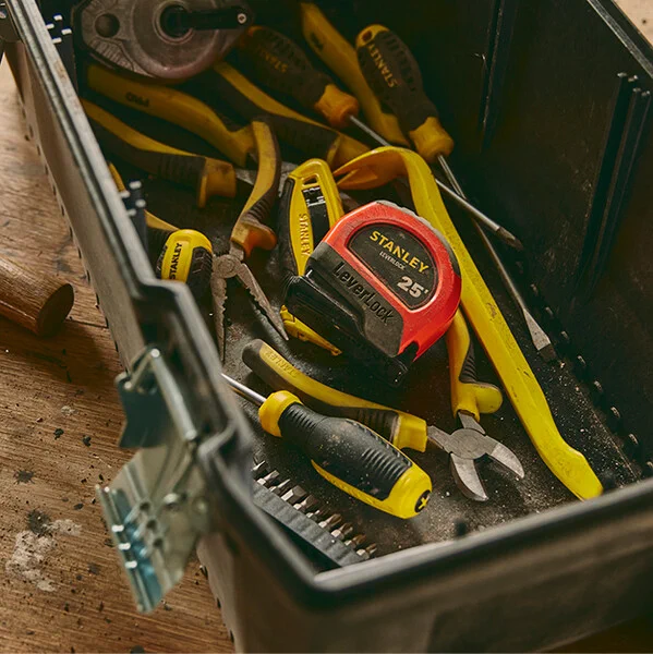 The 25 ft. High Visibility Magnetic LEVERLOCK® Tape Measure resting in a tool box with other hand tools. 