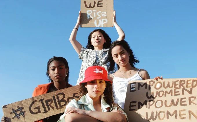 Four women of different races holding empowering signs