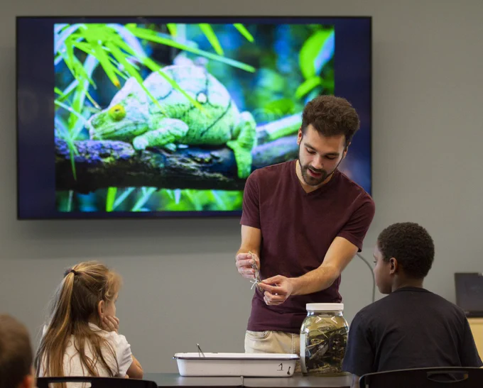 Greg Pandelis, curator of the UTA ARDRC, shows a pair of kids a preserved chameleon.