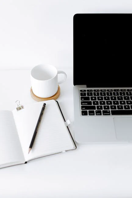Laptop computer with pen, notepad and coffee cup