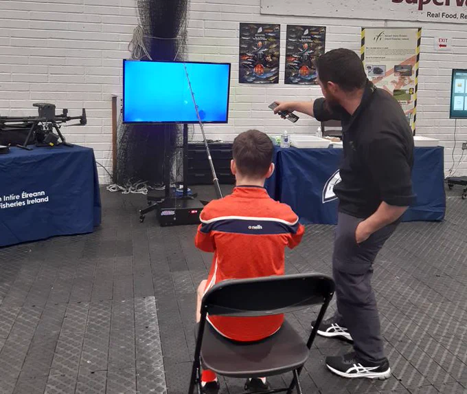 A visitor reeling in a fish at Inland Fisheries Ireland's angling simulator