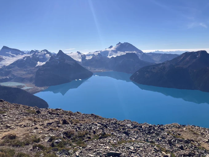 A photo of a bright blue lake, surrounded by mountains and glaciers on all sides.