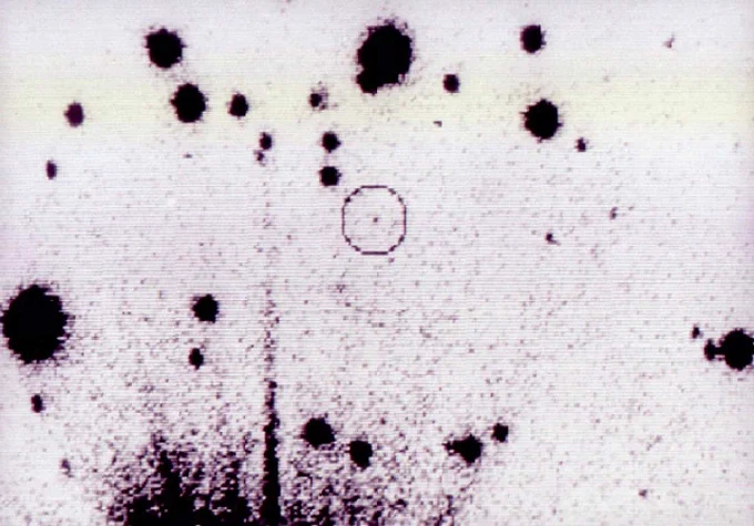 Black circles of various sizes on a white background. One of the smaller dots is circled by a reddish circle to indicate that it is important.