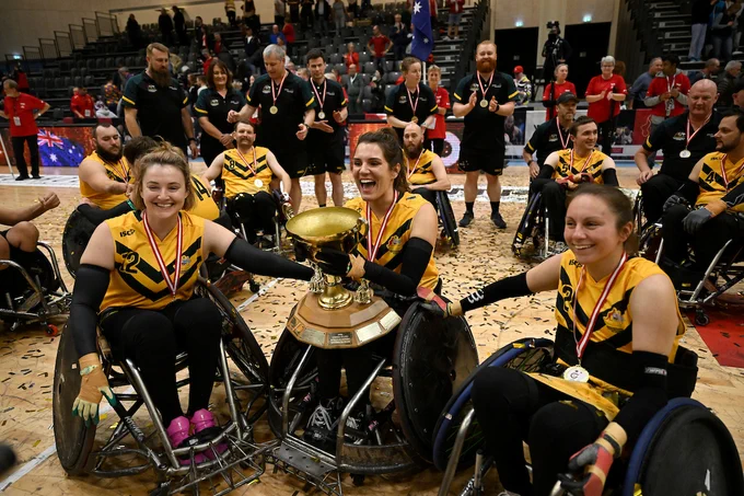 Australian female players holding the trophy and smiling. 