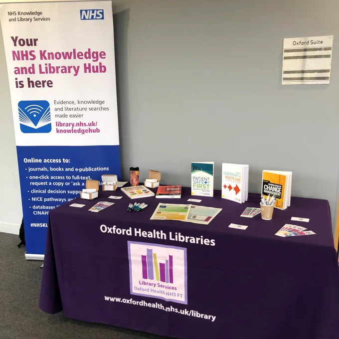 Table with Oxford Health Libraries tablecloth. Books and printed copies. 