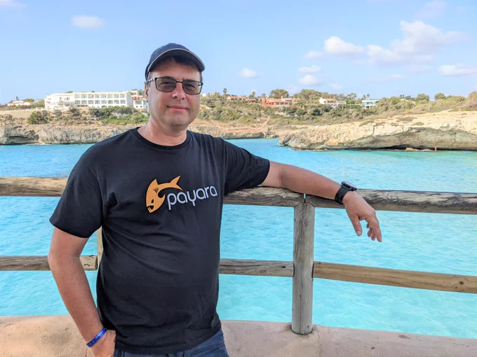 Petr poses in Payara merchandise in front of lake
