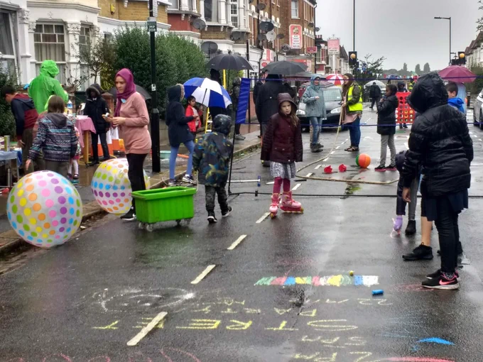 A typical north london terraced street with children playing in the street. They are protected from drivers by a physical barrier.