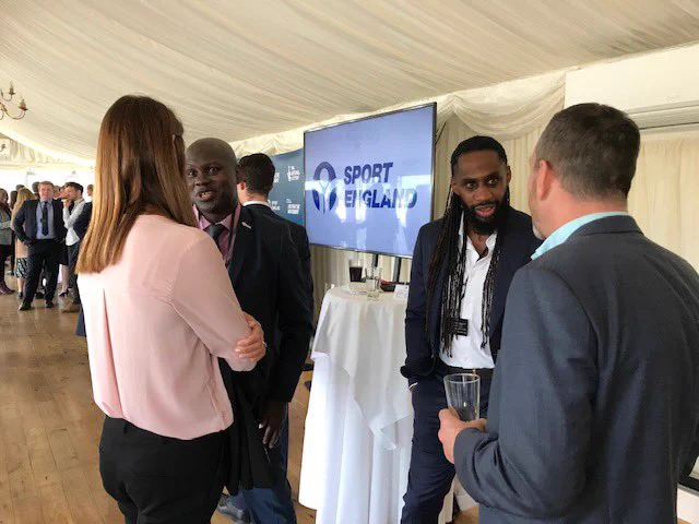 People chatting at Parliament Reception worth Sport England banner in the back.