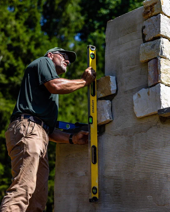A Pro using a STANLEY® FATMAX® Aluminum Box Beam Level to make sure the fireplace he is building is level. 
