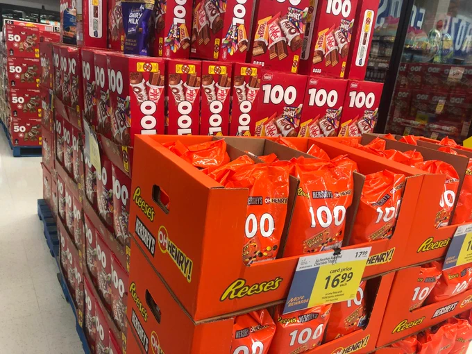 Pallets of boxes of halloween candy stacked in a supermarket aisle