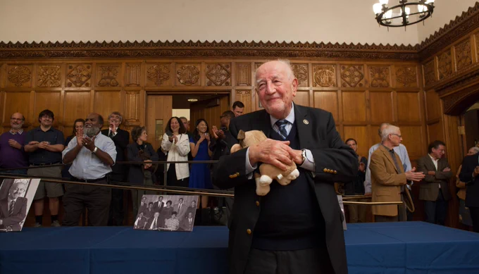 85th birthday celebration, 2017. Guido in the dining hall with row of faculty standing in the background, applauding.