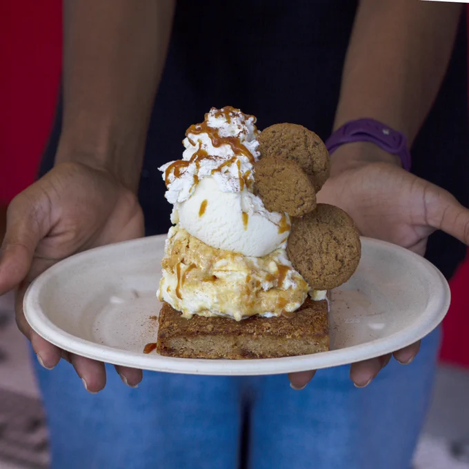 A pair of hands holds a paper plate with a Pumpkin King Sundae on it.