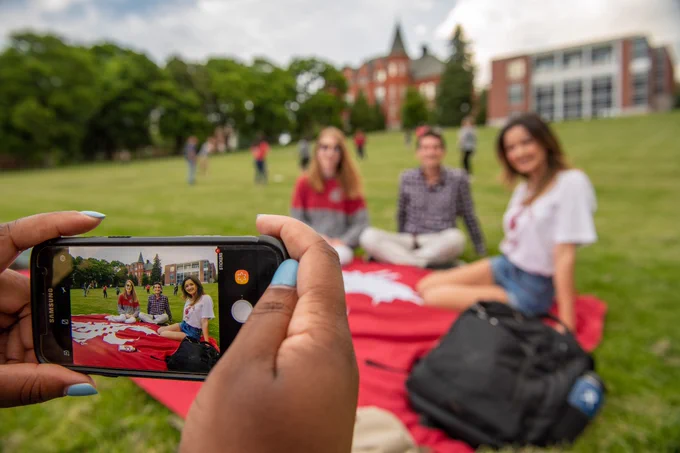 Students sit on a crimson blanket on green grass while they enjoy the late afternoon on the campus of Washington State University Pullman, Wednesday, June 5, 2019. Credit Robert Hubner, WSU Photo Services. 