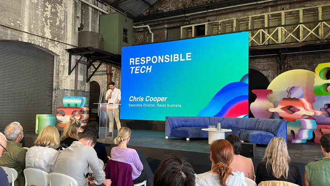 Host Chris Cooper talking in front of the crowd with a large screen behind him with the title Responsible Tech. It’s a colourful scene with lots of blues and greens.