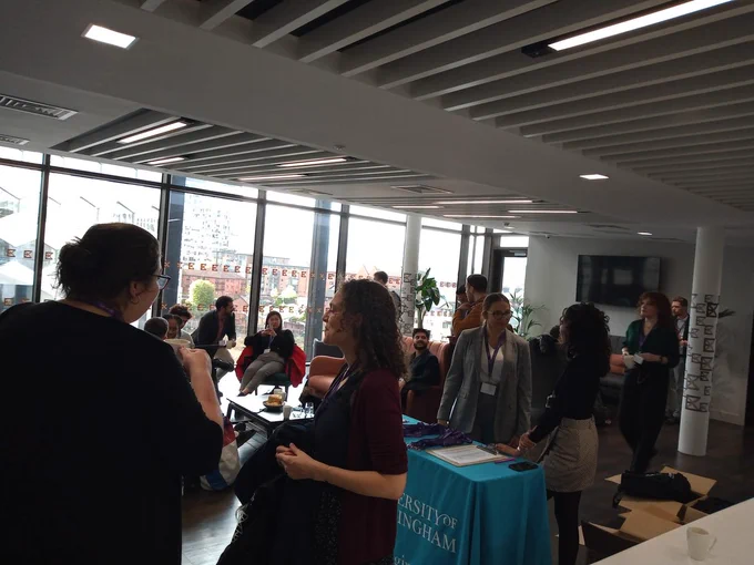 the picture show the registration and coffee room with attendees arriving and chatting around