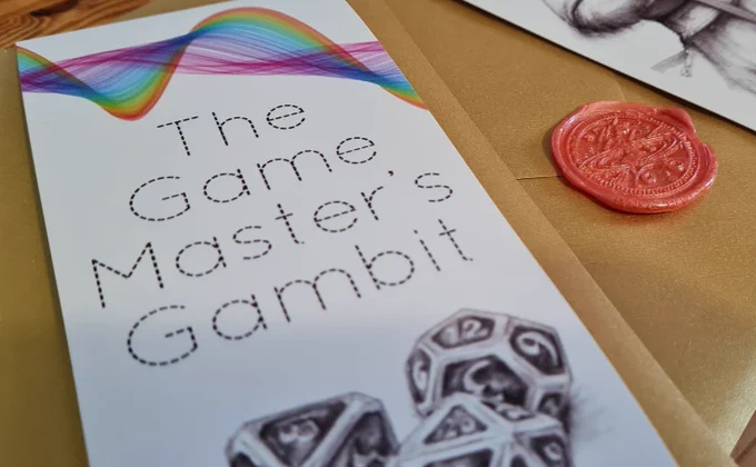 Image of a sealed copy of The Game Master's Gambit. Visible is the shiny gold envelope, wax seal, and sleeve featuring the title, a rainbow effect, and a pencil drawing of some dice.
