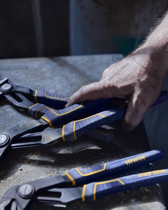 An image of someone grabbing a Vise-Grip® GROOVELOCK™ 10-in Electrical V-jaw Plier off of a metal surface.