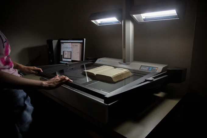 Image of a person scanning a book on a flatbed scanner