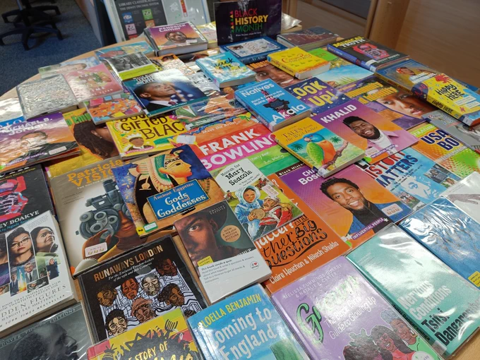 A table covered in books, including 'Ancient Egyptian gods and goddesses', 'Frank Bowling', 'Grown', 'Coming to England', 'Khalid', 'Natives' and more