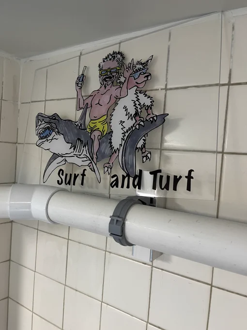 A stained glass panel of Guy Fieri and a llama wearing sunglasses riding a great white shark over the words "Surf and Turf."