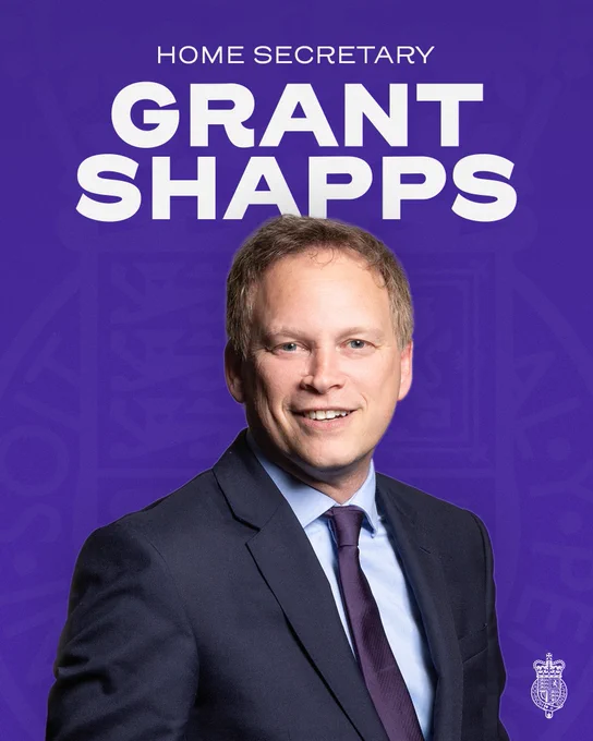 A graphic with text reading: 'Home Secretary Grant Shapps' with the Home Office crest logo watermark in the background. Grant Shapps' official parliamentary portrait appears in the centre of the graphic.