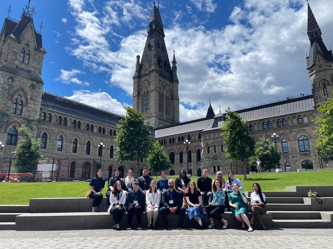 Group photo Youth Council members and OCSA staff seated with the West Block of Parliament Hill in the background.